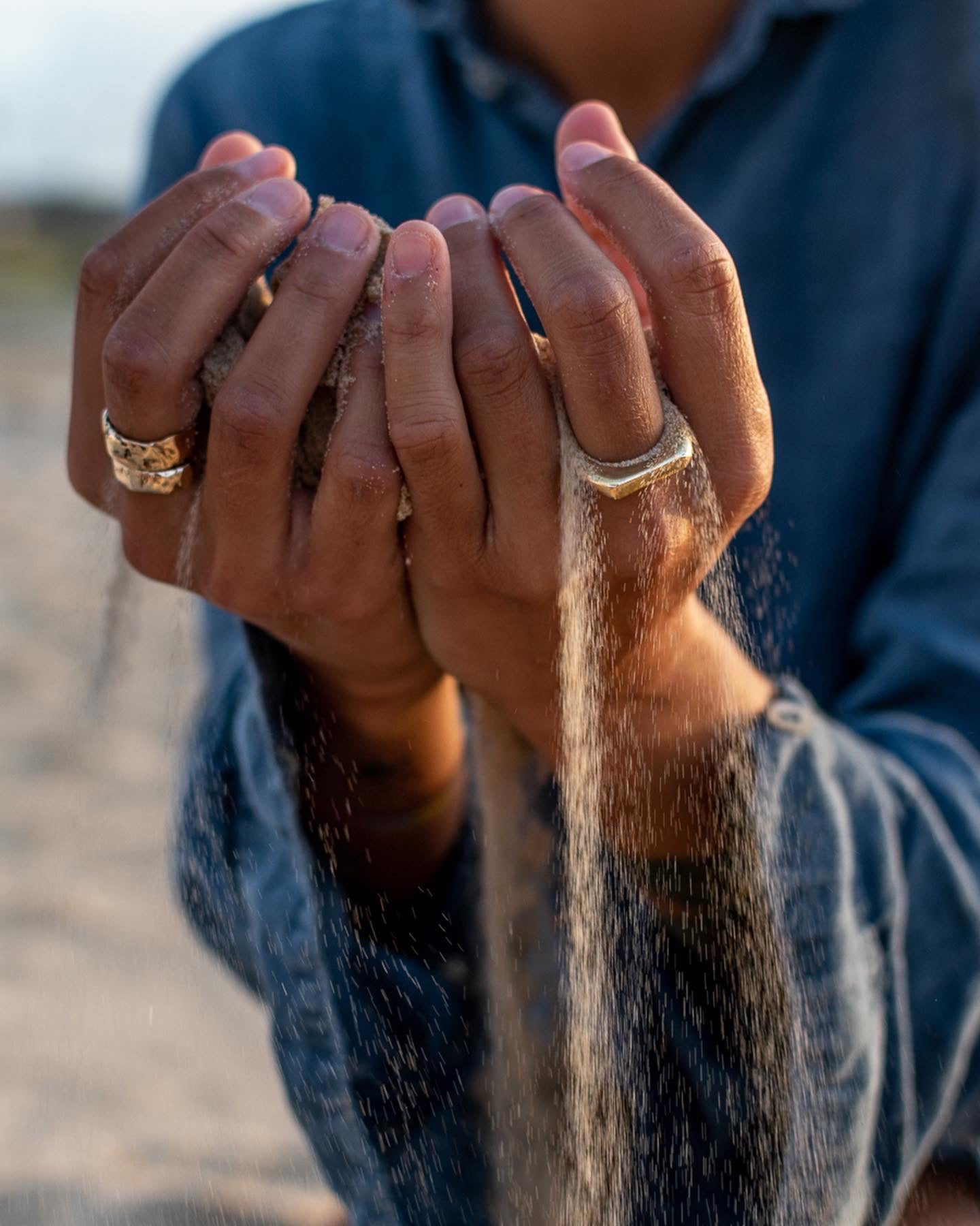 mani con indosso anelli di esterjewels lasciano scivolare la sabbia tra le dita