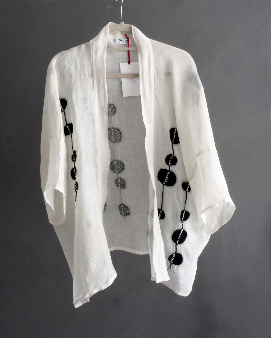 giacca kimono bianca con disegno in nunofeltro nero appesa