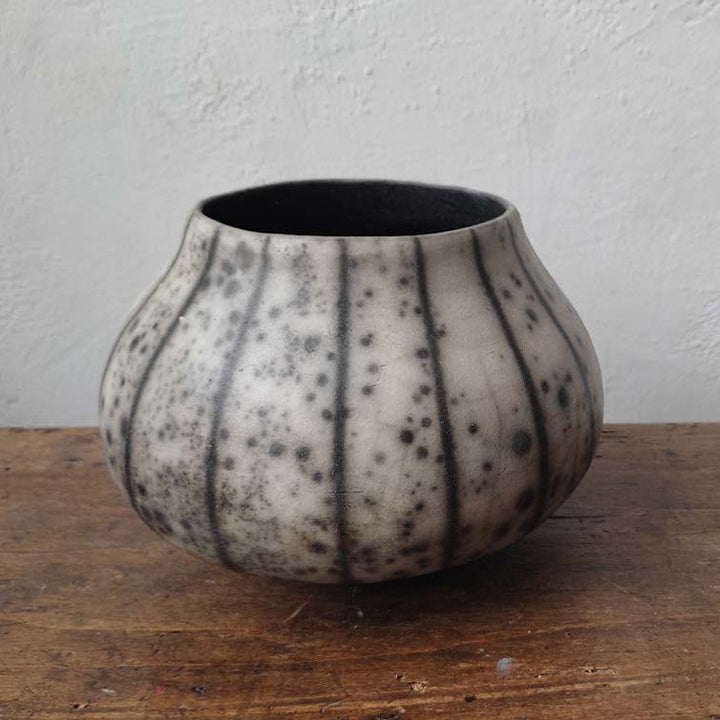 vaso fatto a mano in ceramica raku appoggiato su un tavolo in legno